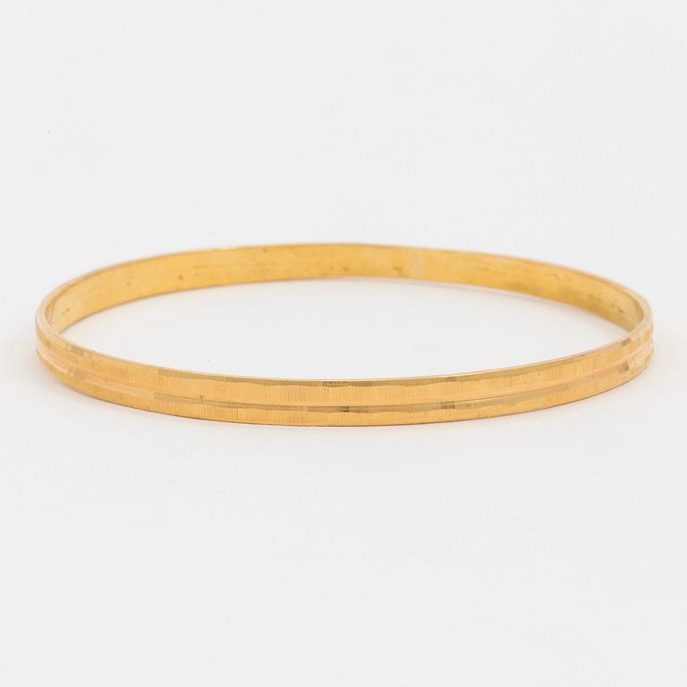 A bangle with a textured surface. 14K gold.