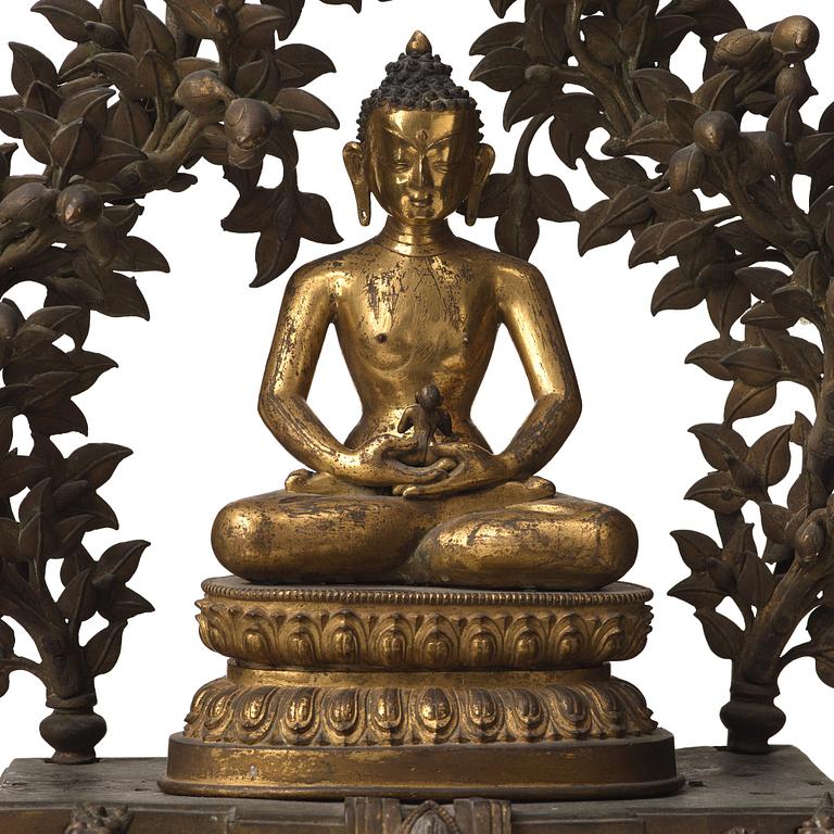A large Nepalese gilt bronze buddha on a throne with mandorla, 18/19th Century.