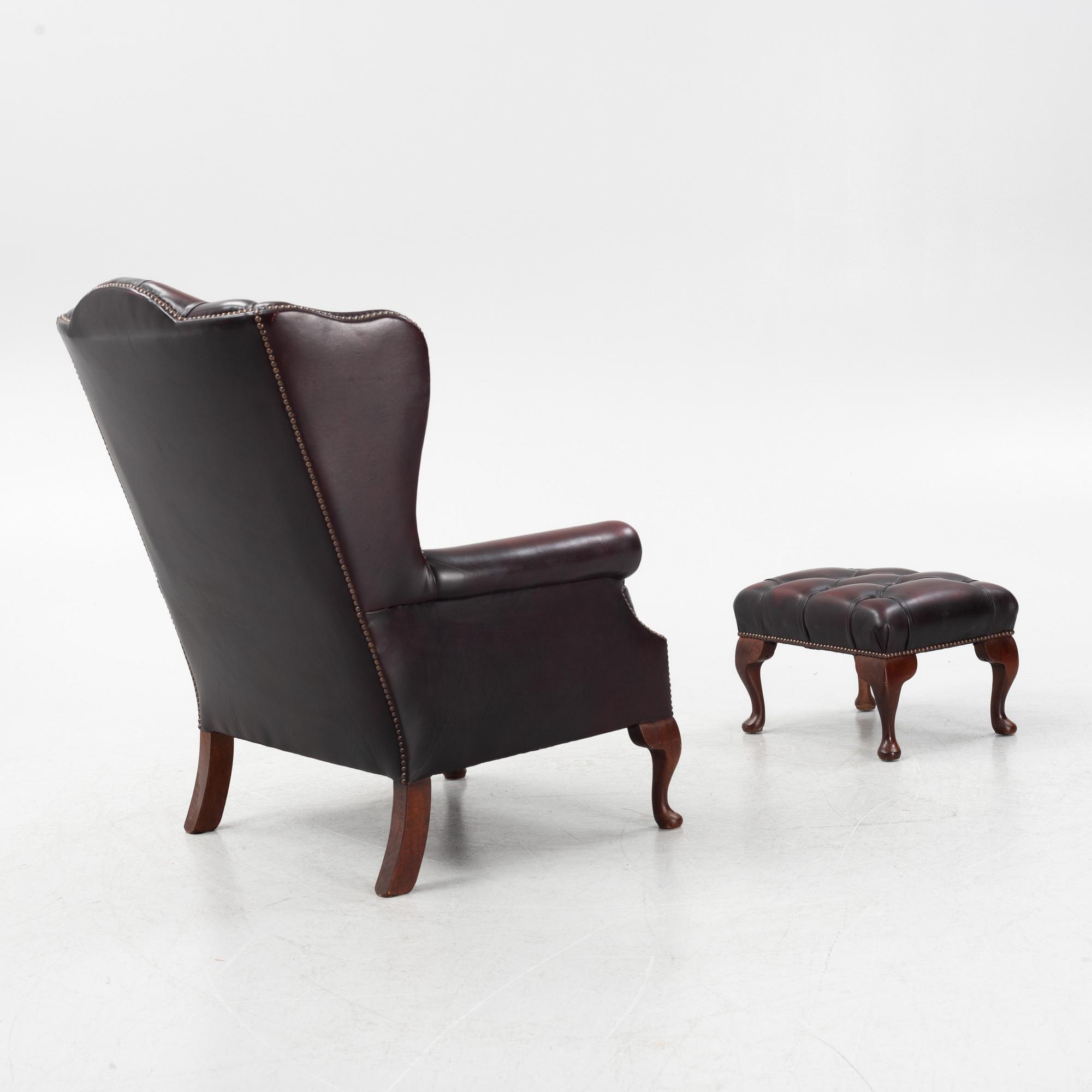 A leather upholstered wingback chair with stool. end of the 20th Century.