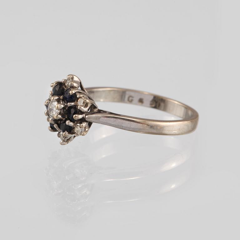 RING, 18K vitguld med en briljantslipad och 6 åttkantslipade diamanter och 6 fasettslipade blåsafirer. Vikt 3,9 gram.