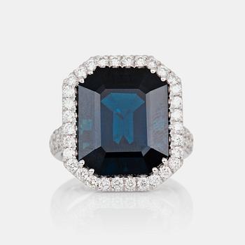 A ring set with a dark greenish-blue sapphire, 16.40 cts, surrounded by 1.08 ct pavé-set brilliant-cut diamonds.