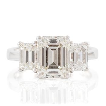 545. An 18K white gold ring set with three emerald-cut diamonds.
