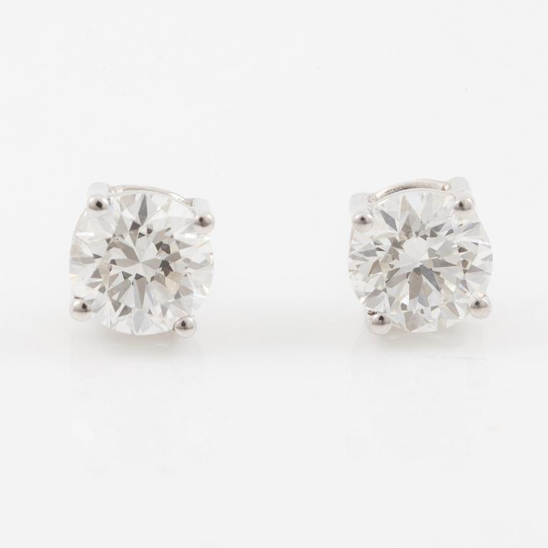 A pair of earrings in 18K white gold set with two round brilliant-cut diamonds.