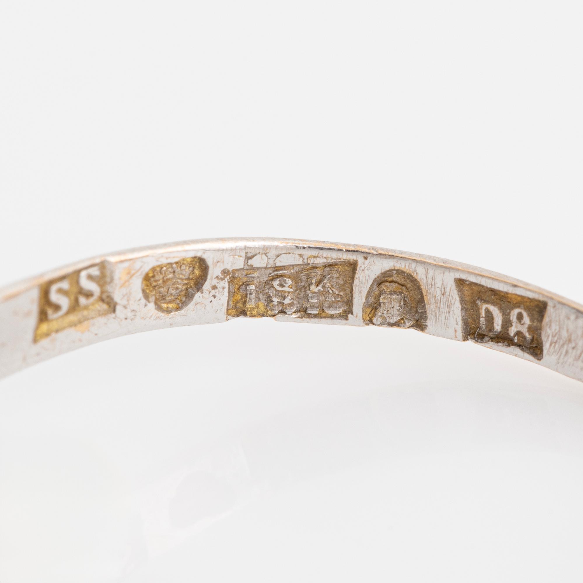 An 18K white gold ring set with a synthetic sapphire and round brilliant-cut diamonds.