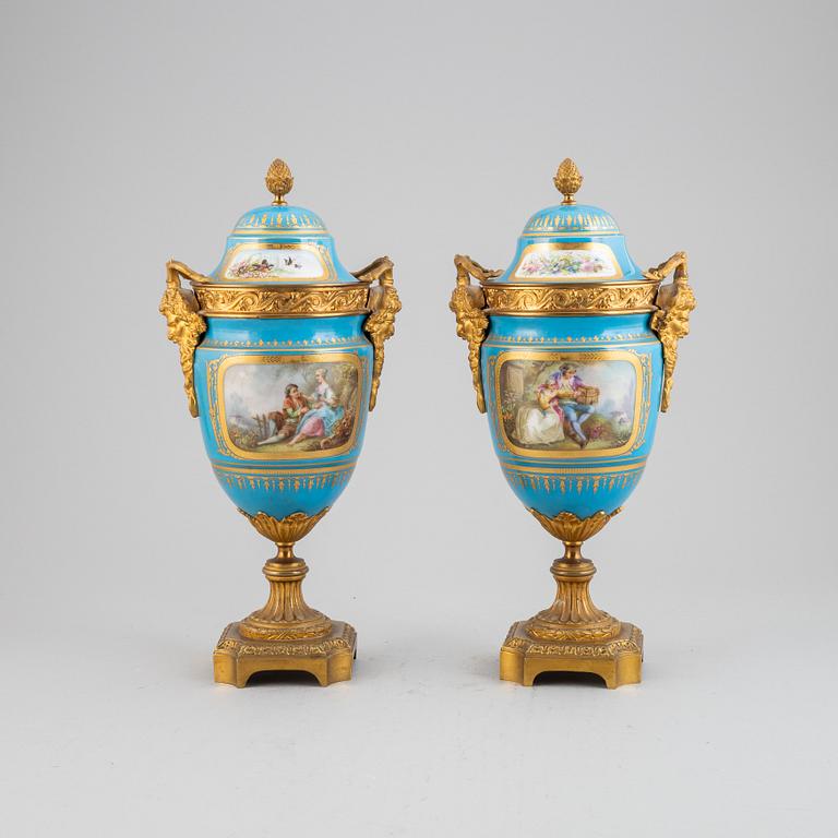 A pair of pordelain and gilt brass urns in teh style of Sevres, 20th Century.