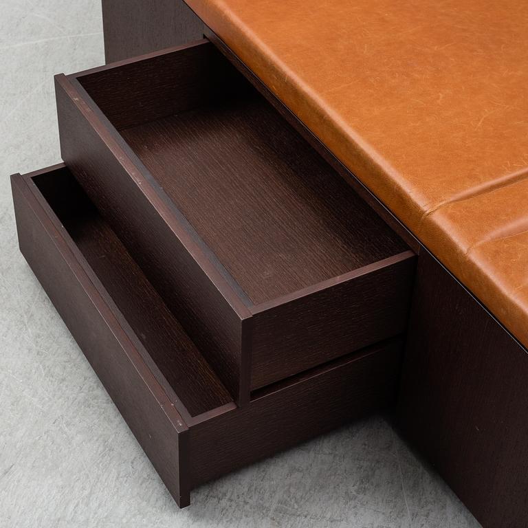 A contemporary bench with drawers and leather upholstery.