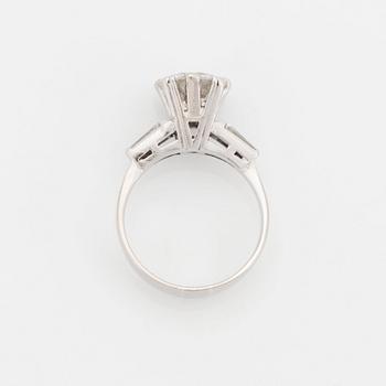 An 18K white gold ring set with a round brilliant-cut diamond and two tapered baguette-cut diamonds.