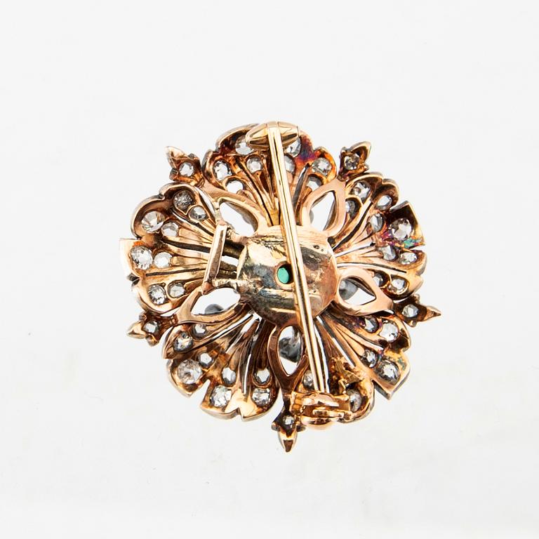 A 14K gold brooch set with a cabochon-cut emerald and old-cut as well as rose-cut diamonds.
