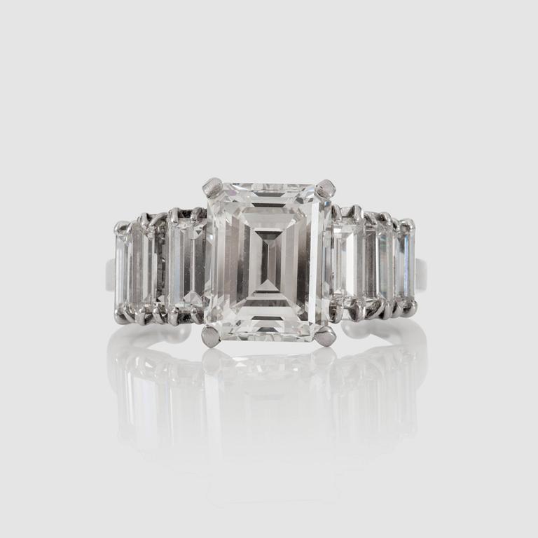 An emerald-cut diamond ring. Center stone 3.12 ct I/VVS2 according to DPL cert. Side stones circa 0.80 ctw.