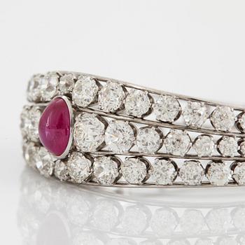 An 18K white gold bangle set with a cabochon-cut ruby and old-cut diamonds.