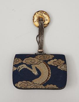 A Japanese embroided tabakoire with a kanamono in the shape of two tigers, a metal chain that holds a carved ivory manjû, second half of 19th Century. Signed.