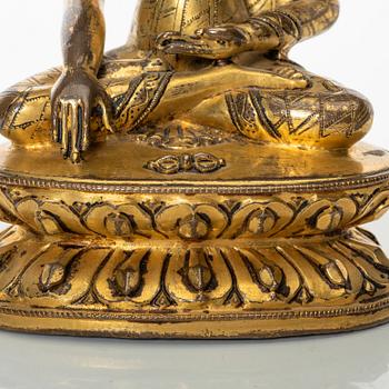 A gilt copper-alloy figure of Aksobhya Buddha, 14th/15th century, Tibet or Nepal.