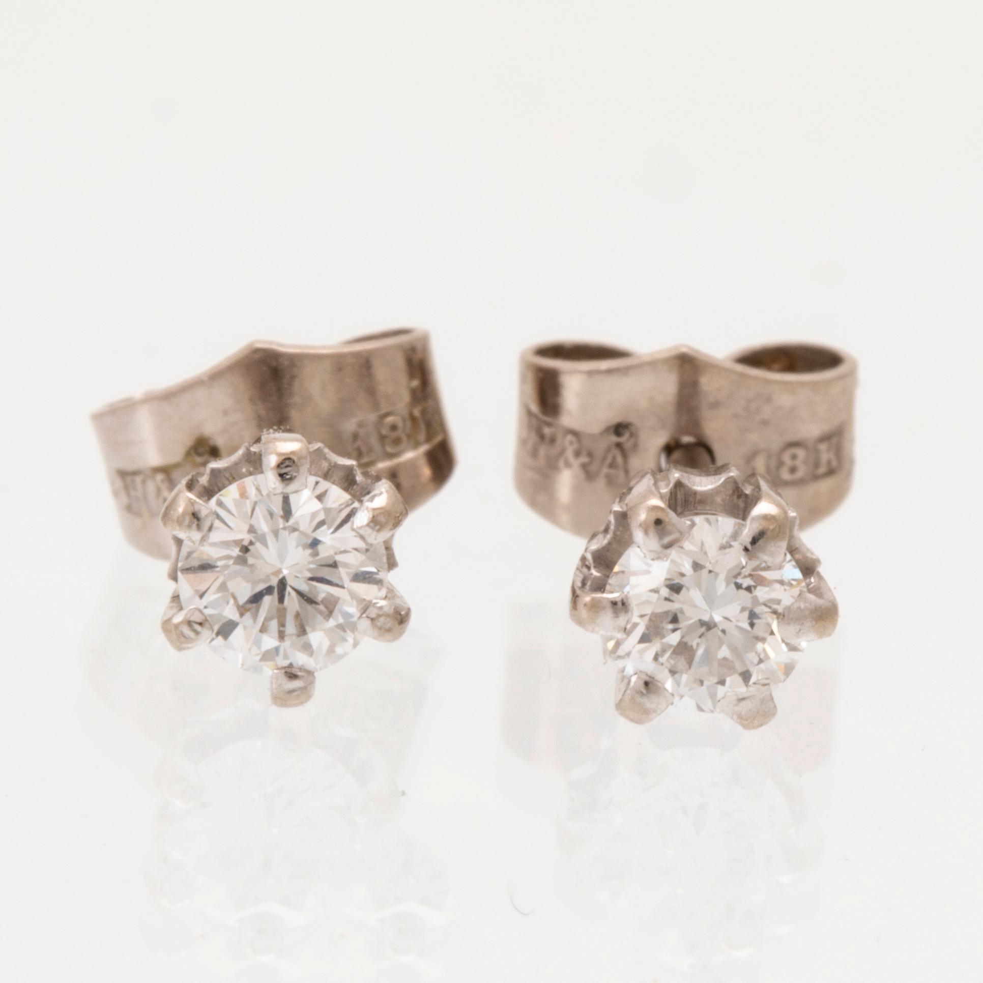 A pair of 18K white gold earrings set with round brilliant cut diamonds.