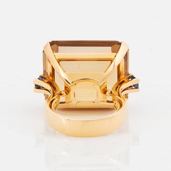 An 18K gold ring set with a faceted citrine and two sapphires.