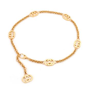 GUCCI, a gold colored mongrammed chain.