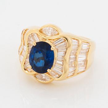An 18K gold Junod ring set with a facted sapphire and tapered baguette-cut diamonds.