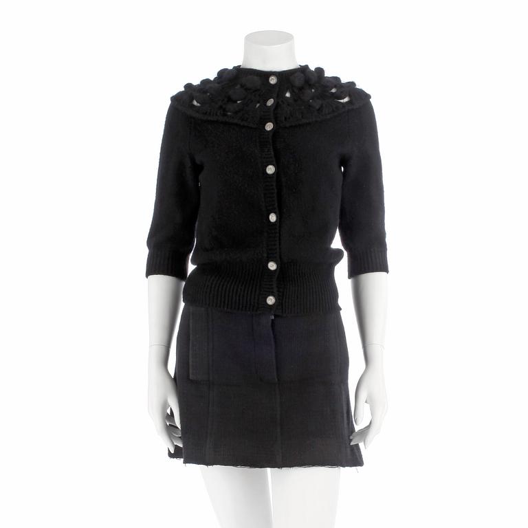 CHANEL, a black cashmere carding and a bouclé skirt.