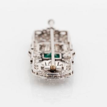 A platinum brooch set with a step-cut emerald and old- and eight-cut diamonds.