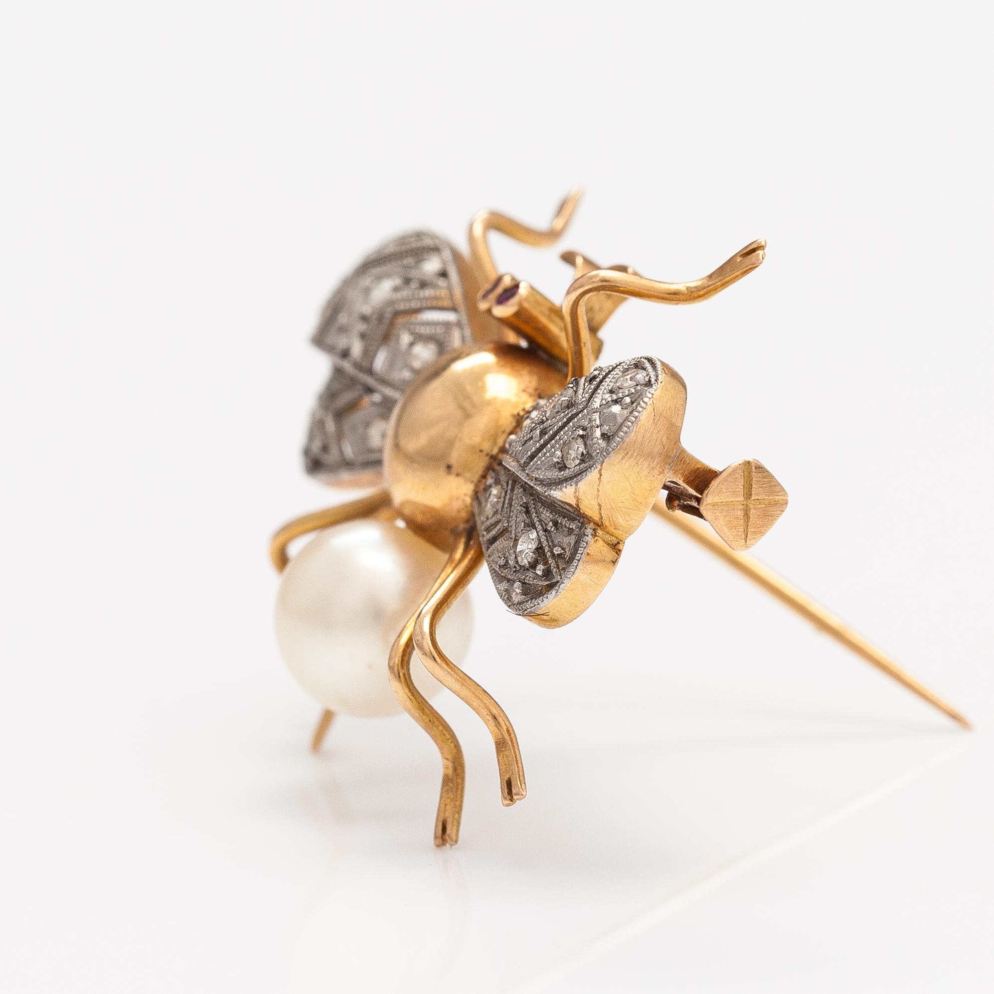 A 15-17K gold brooch with rubies, a cultured pearl and diamonds ca. 0.10 ct in total.