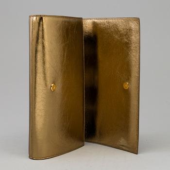 YVES SAINT LAURENT, a gold leather clutch.