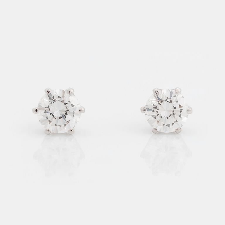 A pair of 18K white gold earrings set with two round brilliant-cut diamonds.