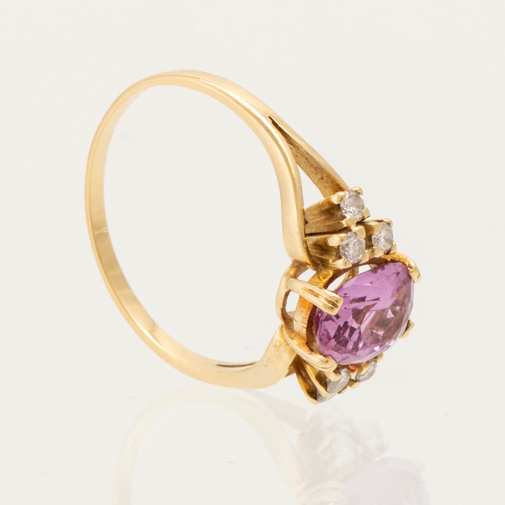 Ring 18K guld med oval fasetterad rosa ädelsten samt runda briljantslipade diamanter.