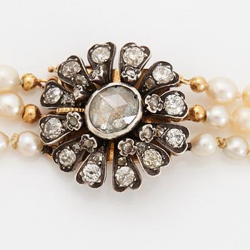 A three strand cultured pearl necklace with a clasp in 18K gold and silver set with rose- and old-cut diamonds.