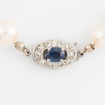 A cultured pearl neckalce with an 18K white gold clasp set with a sapphire and diamonds.