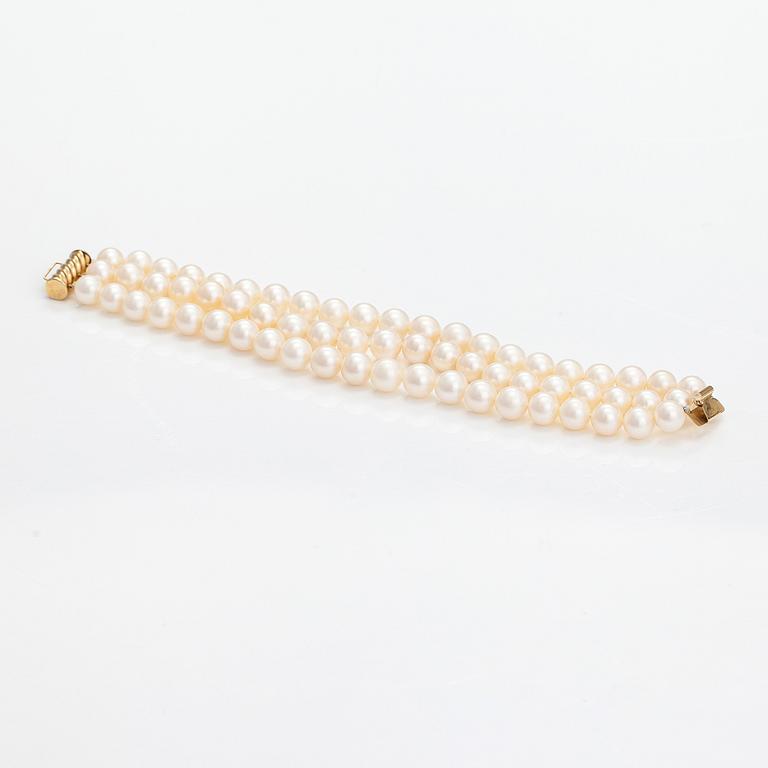 A three-strand pearl bracelet with cultured pearls and a 14K gold clasp.