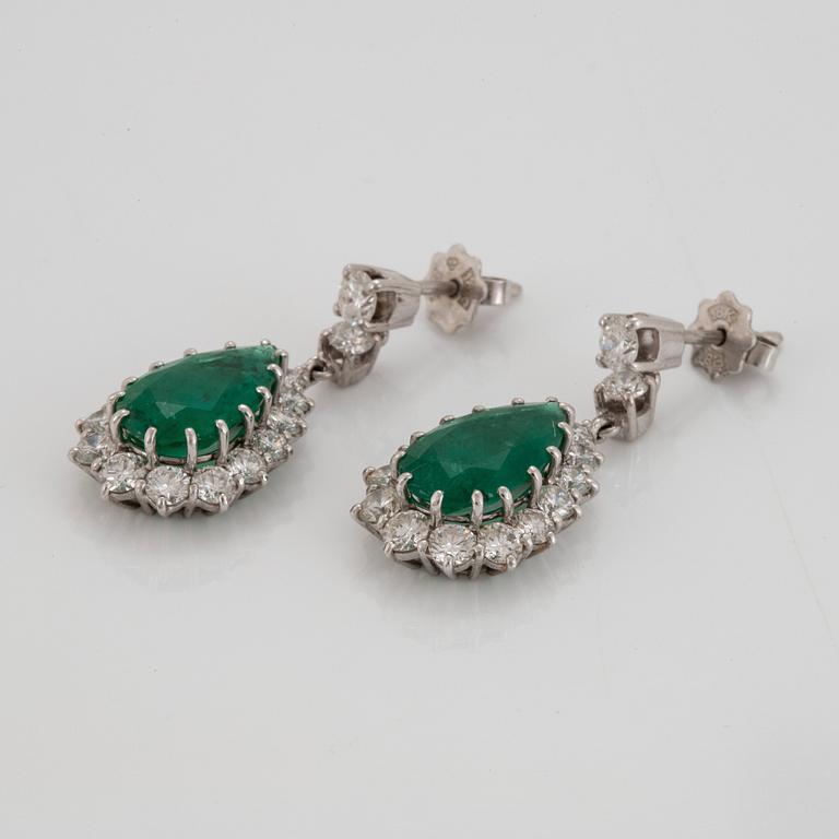 A pair of drop shaped faceted emerald and round brilliant-cut diamond earrings in 18K white gold.