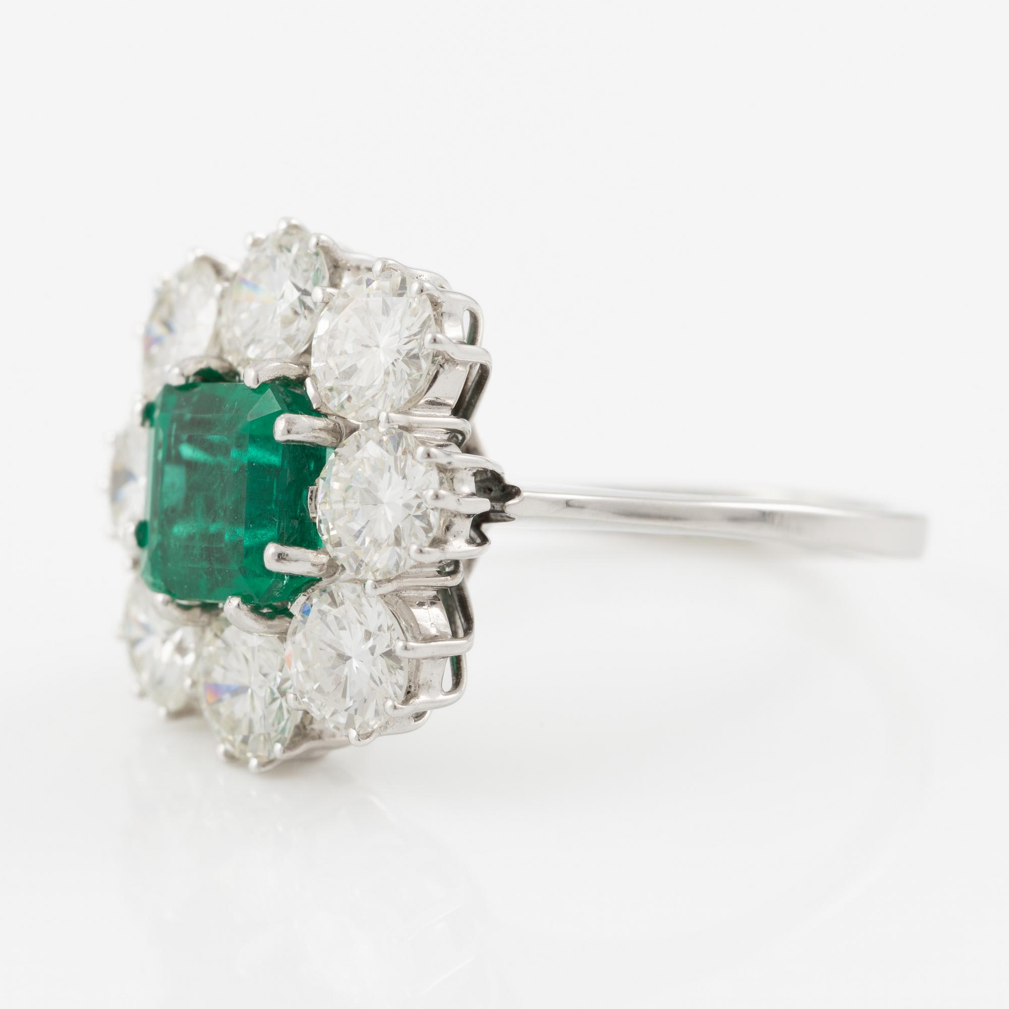 An 18K whitegold ring set with a step-cut emerald and round brilliant-cut diamonds.