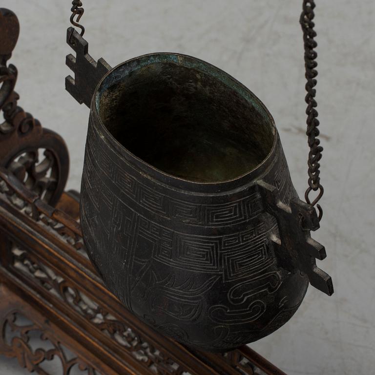 A Chinese bronze temple bell and wood stand, late Qing dynasty.