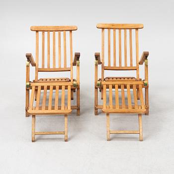 A pair of teak deck chairs and a table, 21st Century.