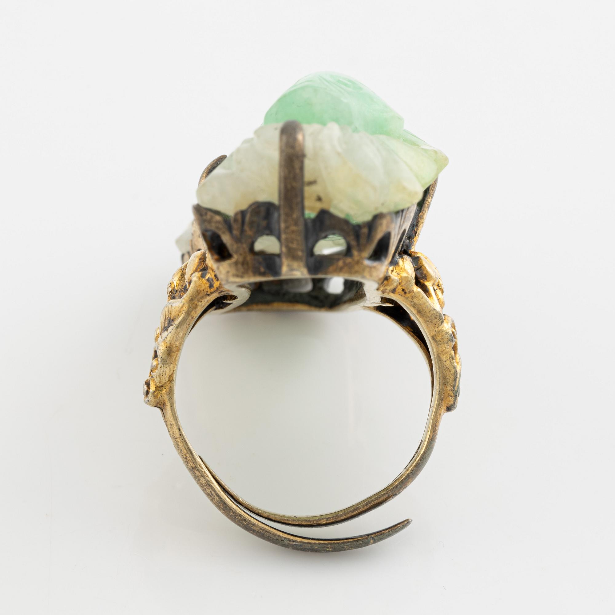 Ring in yellow metal with a white/green stone, possibly nephrite.".