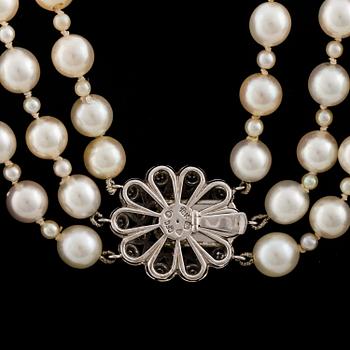 A three strand cultured pearl necklace with a clasp decorated with diamands.