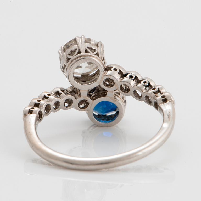 A platinum ring set with old-cut diamonds and a faceted sapphire.