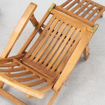 A pair of teak deck chairs and a table, 21st Century.