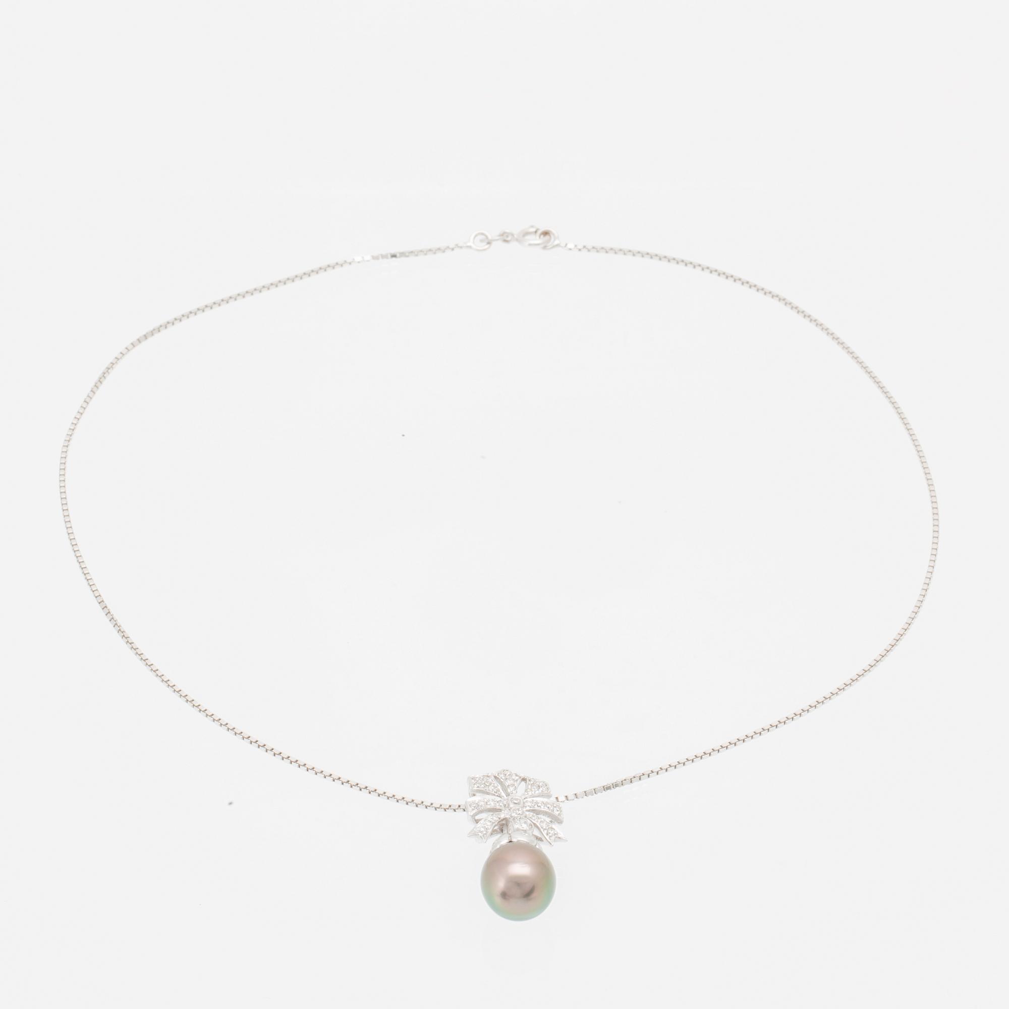 An 18K white gold necklace set with a drop-shaped cultured pearl and round brilliant-cut diamonds.