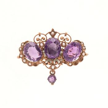 An 8K gold brooch set with seed pearls and faceted amethysts.