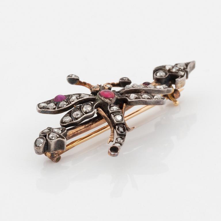 A silver and gold brooch set with rose-cut diamonds and cabochon-cut rubies.
