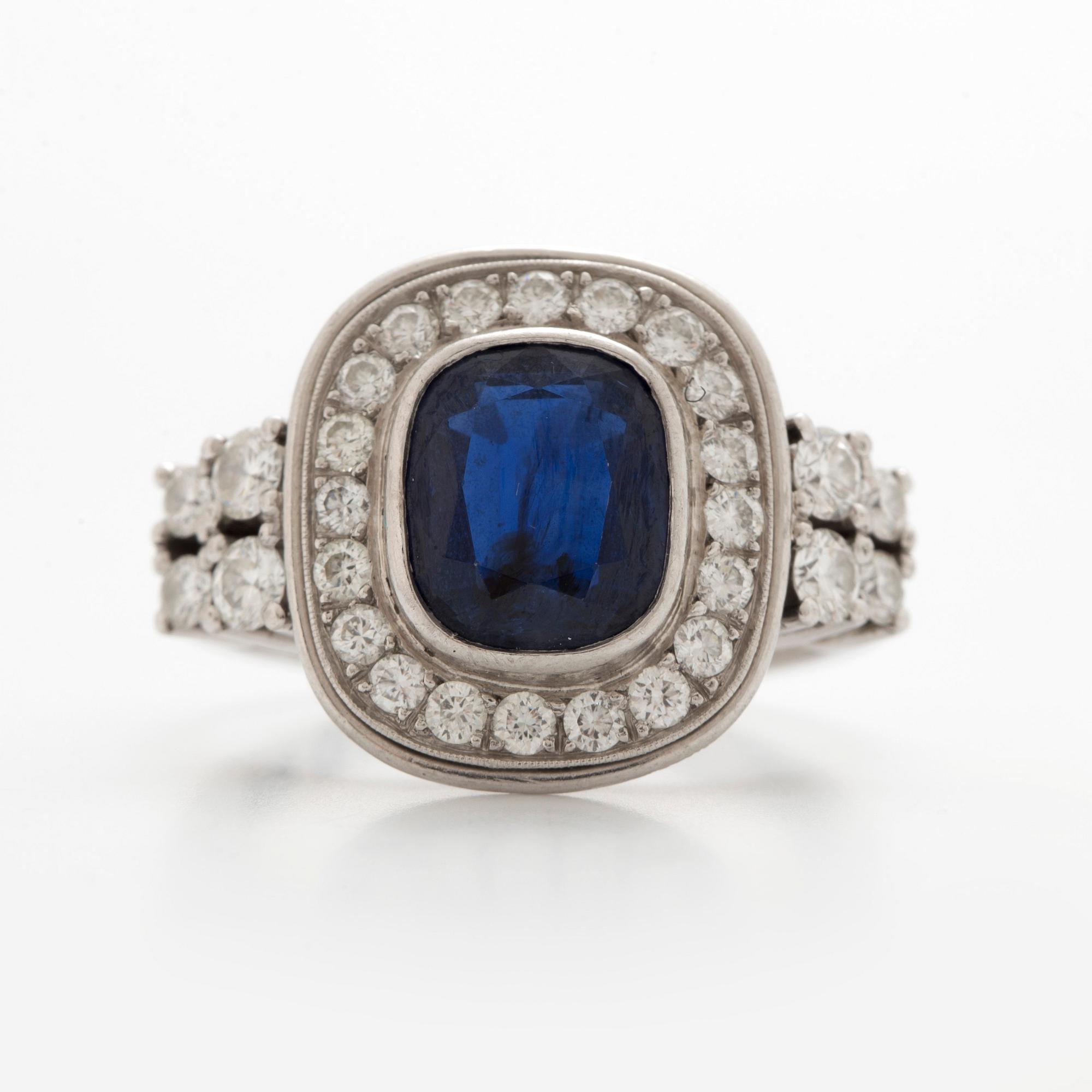 RING, vitguld med en safir ca 2.81 ct och briljanter i karmosé, samt fyra briljanter på var sida vid skenan.