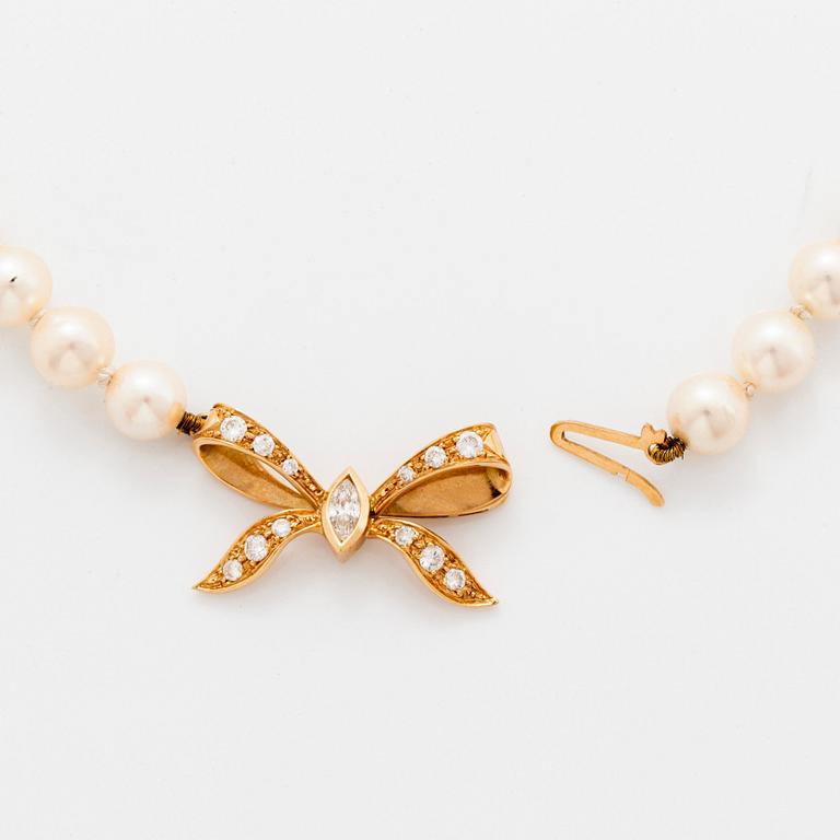 A cultured pearl necklace with a bow clasp in 18K gold set with round brilliant-cut diamonds.