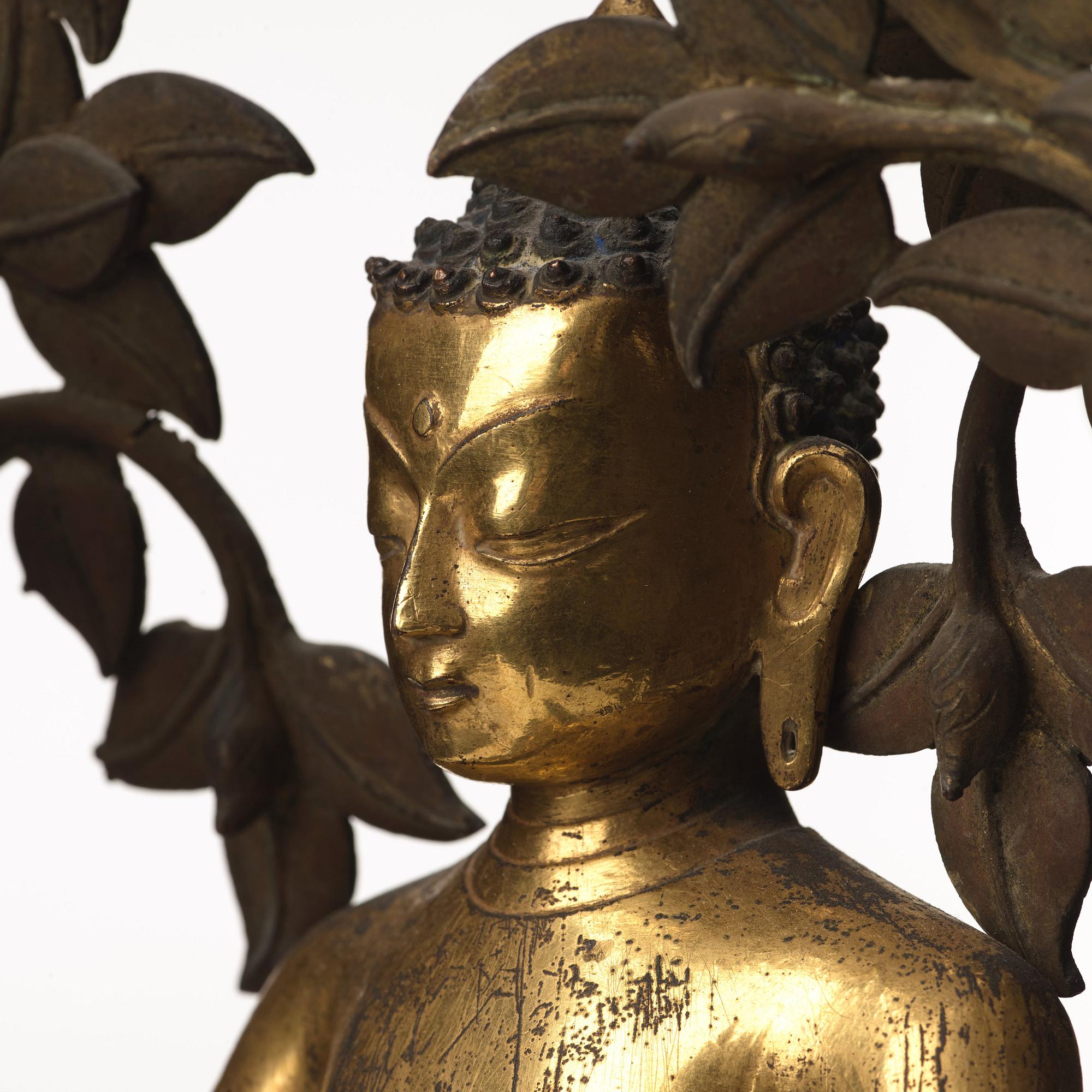 A large Nepalese gilt bronze buddha on a throne with mandorla, 18/19th Century.