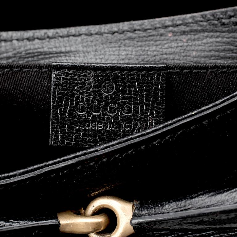 GUCCI, a black embossed leather clutch with a shoulder strap.