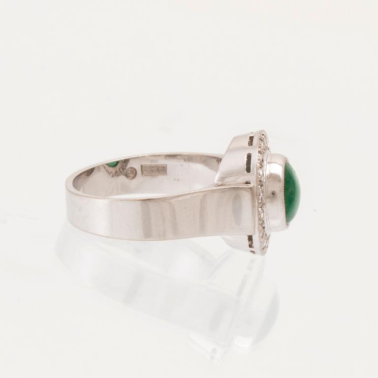 An 18K white gold ring set with a cabochon-cut emerald and round single-cut diamonds.