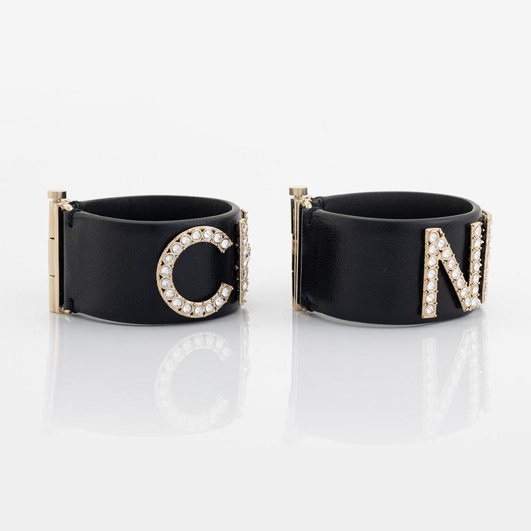 Chanel, a pair of black leather and rhinestone bracelets.