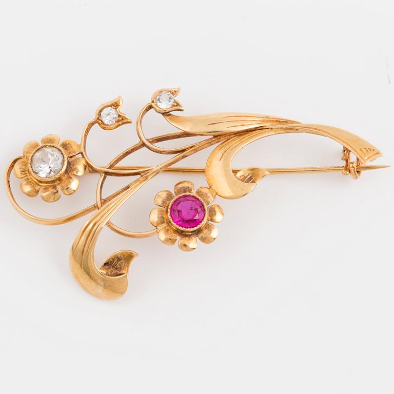 An 18K gold flower brooch set with white stones and a red stone.