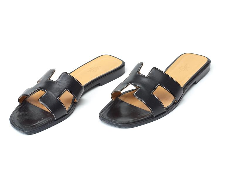 A pair of black leather slippers by Hermès.