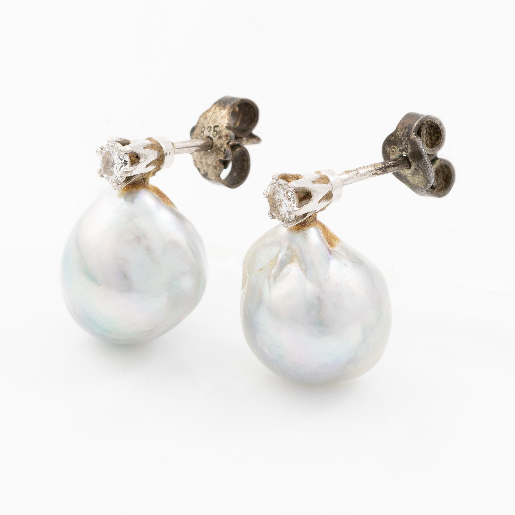Earrings in white gold with drop-shaped grey pearls and round brilliant-cut diamonds.