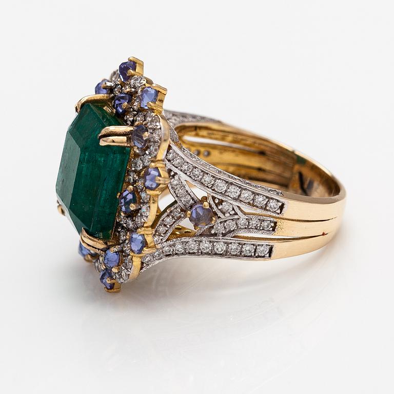 A 14k gold ring with an emerald ca. 6.39 ct, tanzanites and diamonds ca. 1.25 ct in total.